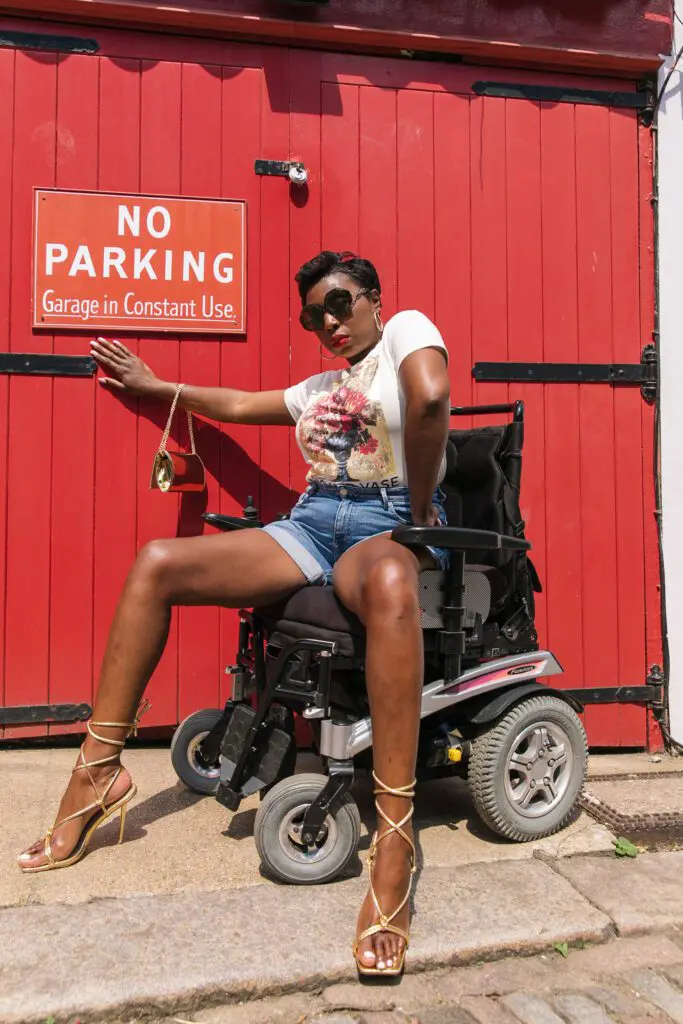 A Lady sitting on a wheelchair outside of a red gate